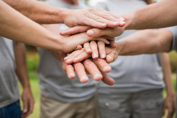 Quelle: © WavebreakmediaMicro/Fotolia Eine Gruppe Menschen steht zusammen und legt die Hände aufeinander als Zeichen der Verbundenheit
