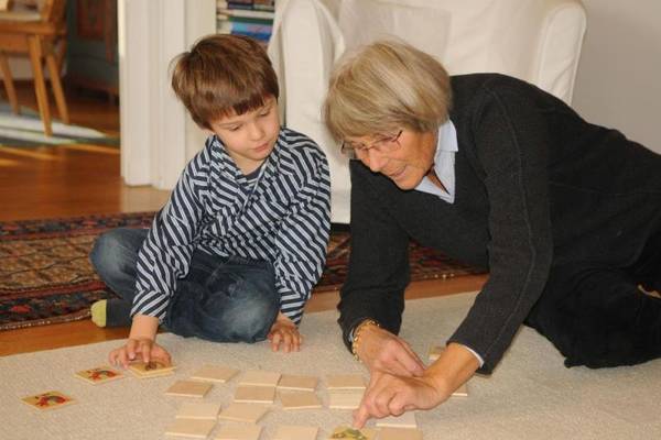 Eine ältere Frau sitzt neben einem kleinen Jungen auf dem Boden und puzzelt mit ihm