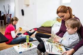 Eine Frau hat ein Kind auf dem Schoß und liest ihm vor aus einem Buch