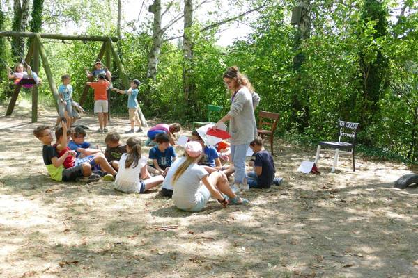 Kinder sitzen auf einem Sandplatz und spielen
