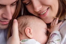 Ein Mann und eine Frau halten zusammen ein Baby im Arm